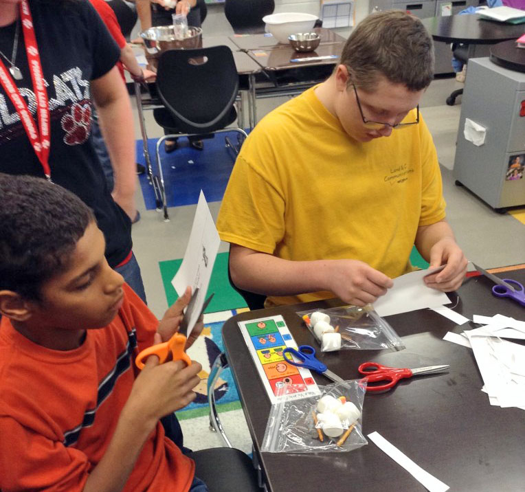 Students clipping paper with scissors