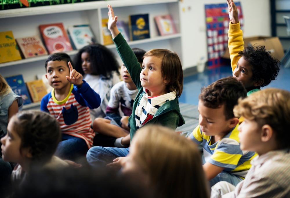 Preschool students raising their hands in a classroom
